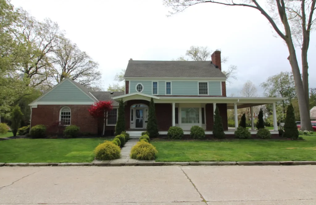 picture of front of house taken from the street with new light blue siding recently installed.