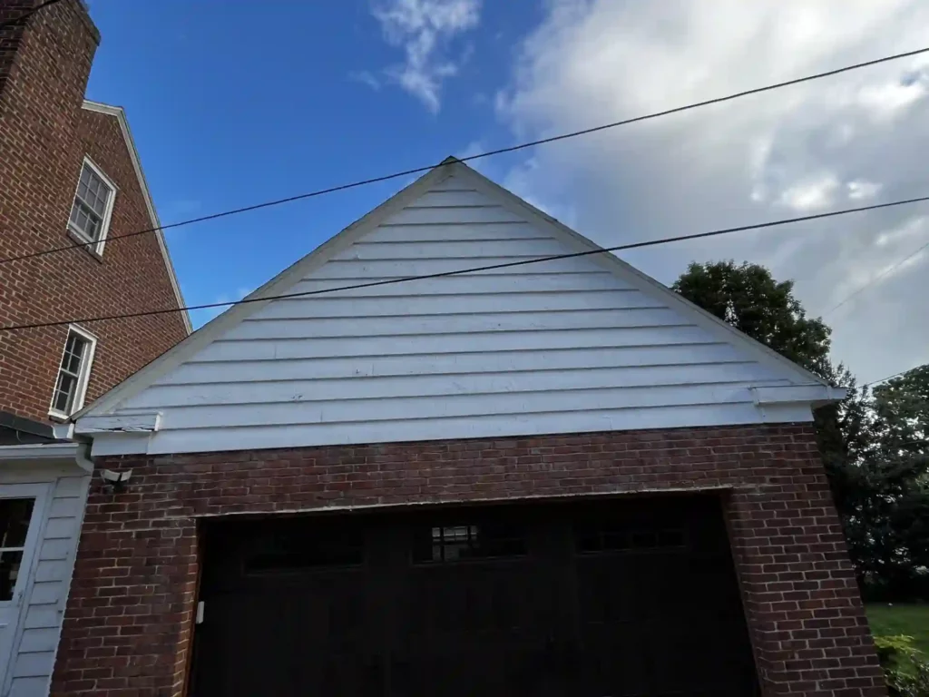 old worn out white siding above garage door