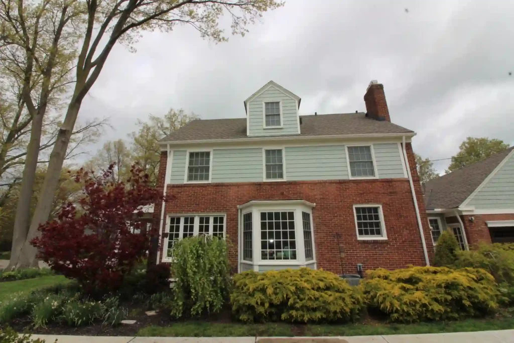 new light blue siding recently installed on side of house with shrubs and bushes in view