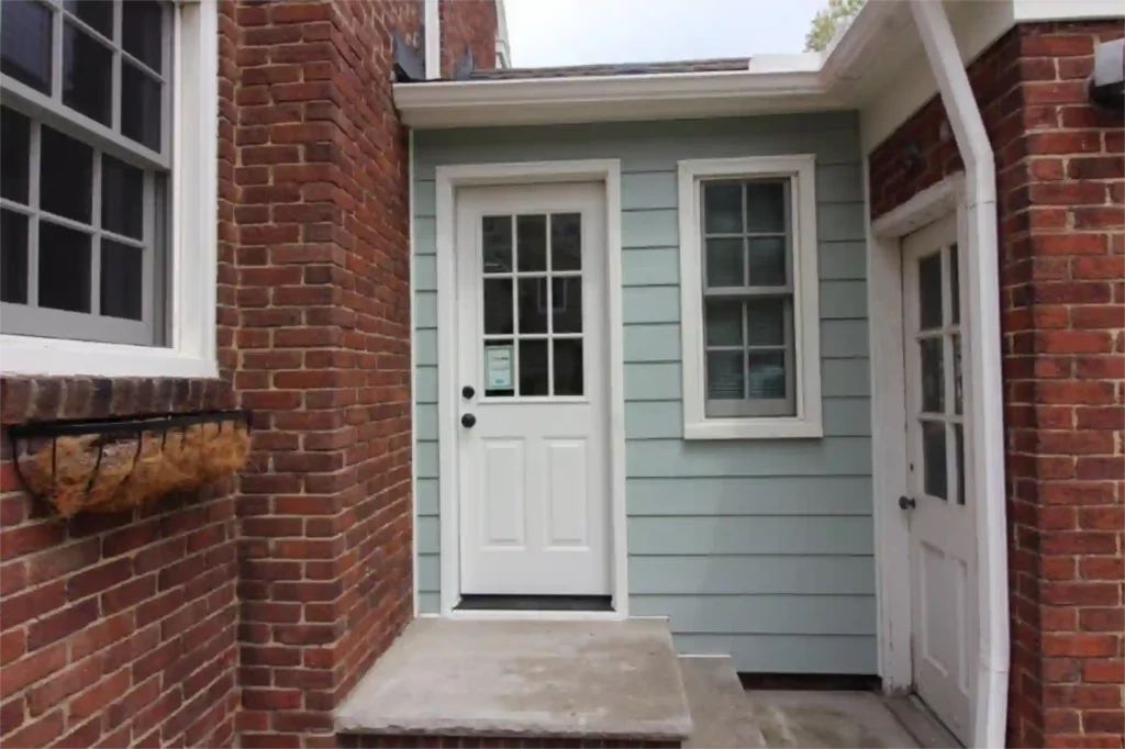 grade side door with new light blue siding recently installed