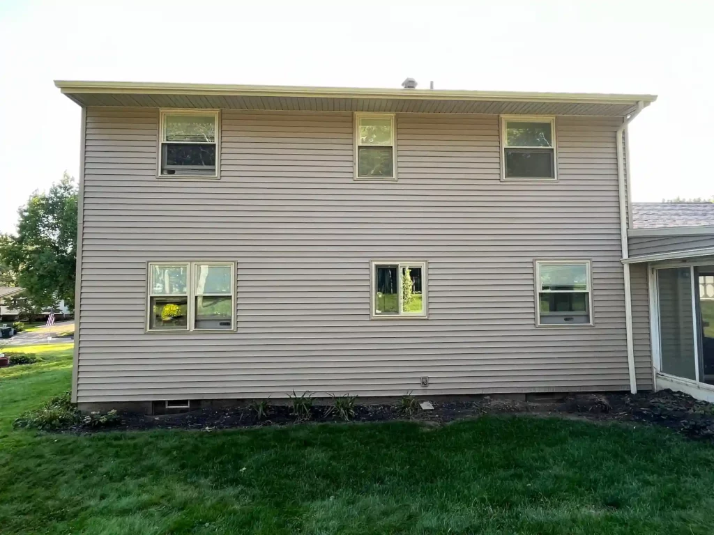 picture of the side of a two story home showing new tan siding and many windows