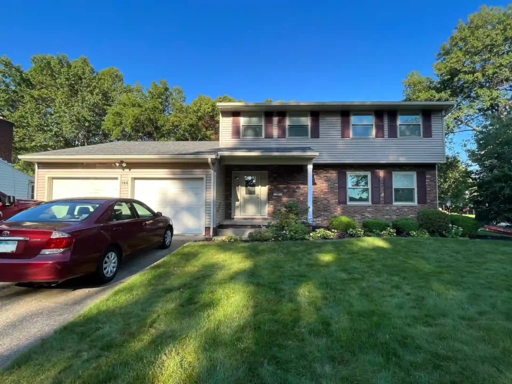 picture of a ranch style home from the street showing new tan siding