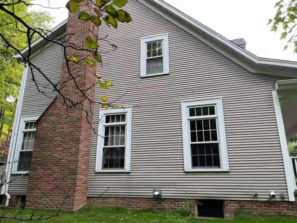side of home with brick chimney and new tan vinyl siding